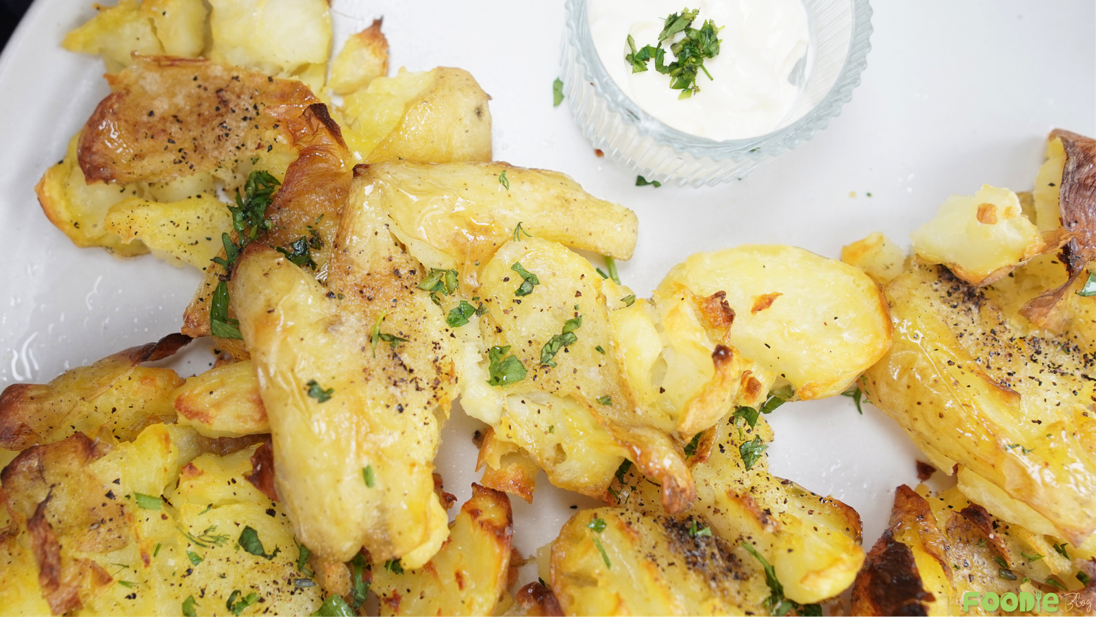 Crispy smashed potatoes with golden edges and parsley on a white plate