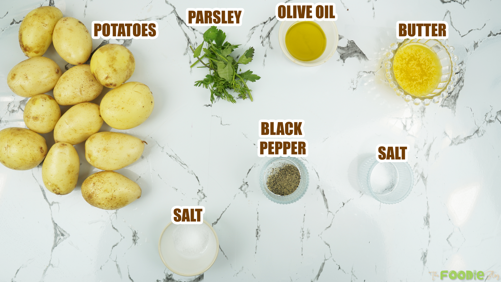 Potatoes, parsley, olive oil, butter, salt, and black pepper on a countertop