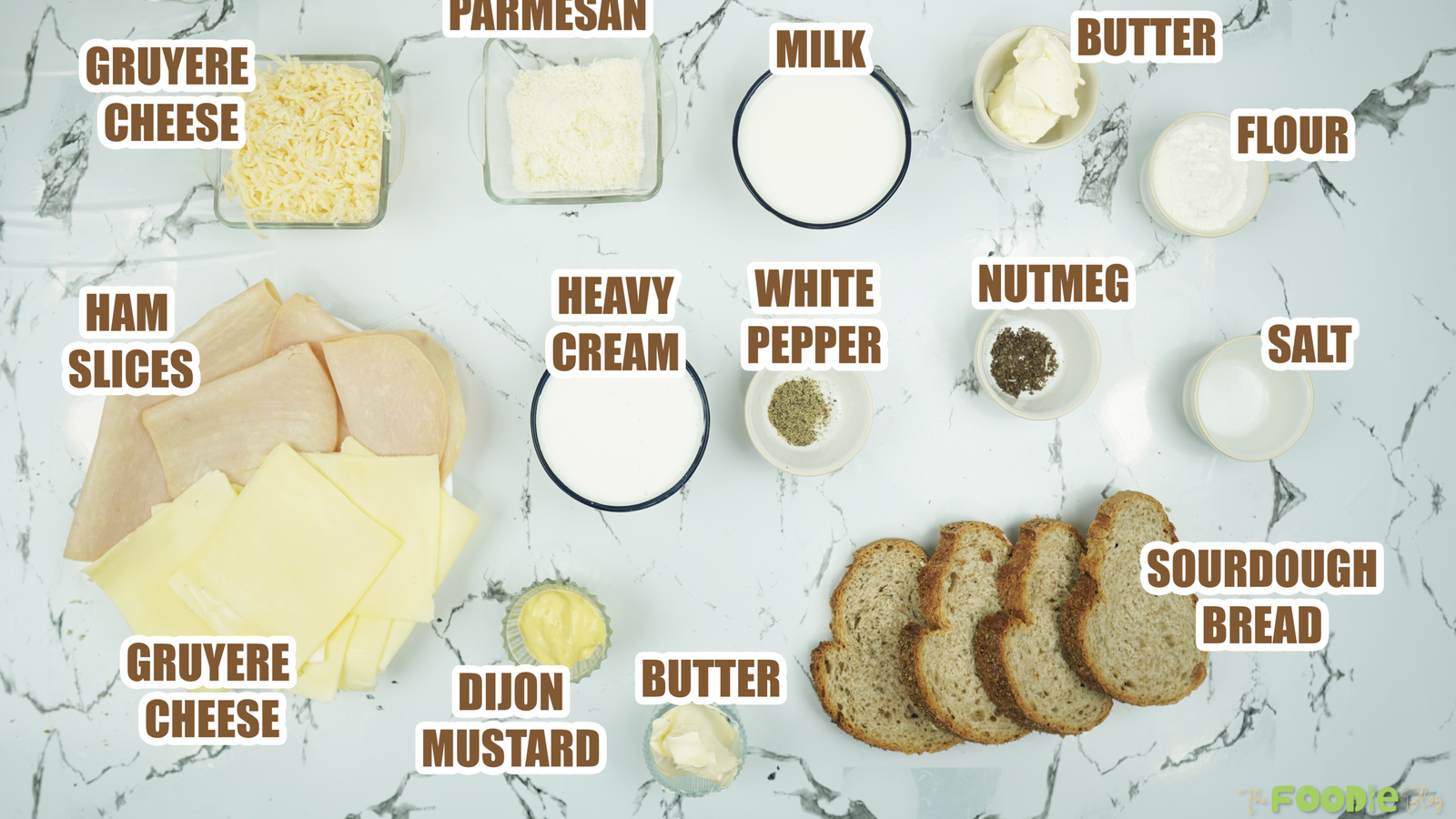 Overhead view of bread, ham, cheeses, milk, cream, butter, flour, mustard, and seasonings on a counter