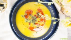 Close-up overhead shot of smooth lentil soup with paprika oil swirls and parsley