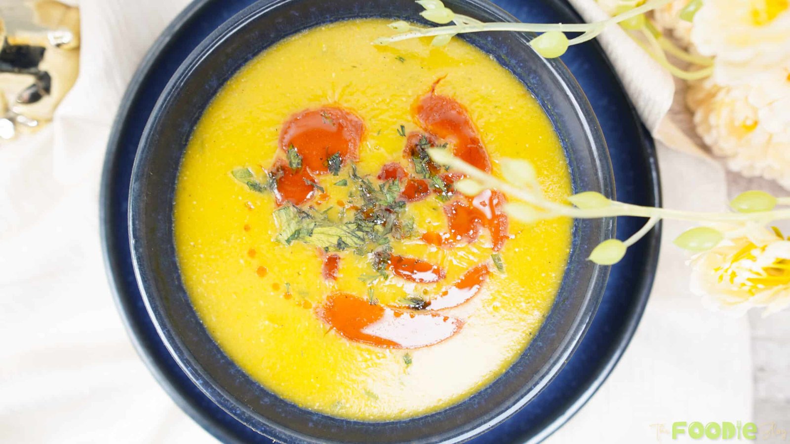 Close-up overhead shot of smooth lentil soup with paprika oil swirls and parsley