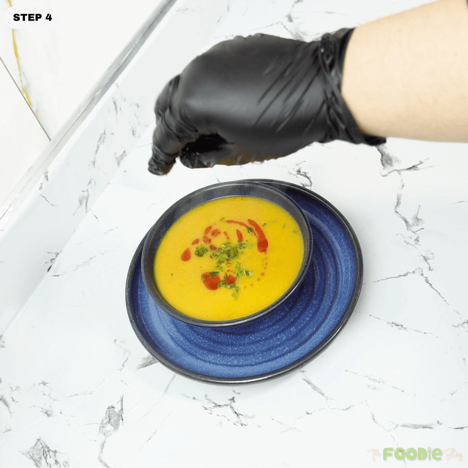 Bowl of lentil soup topped with paprika and parsley while olive oil is drizzled over