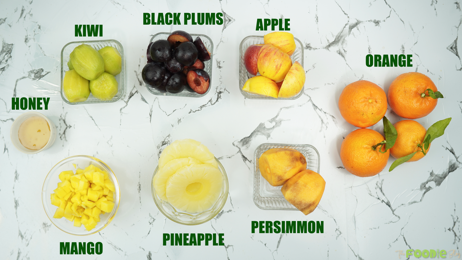 Overhead view of kiwi, plums, apples, oranges, mango, pineapple, persimmon, and honey