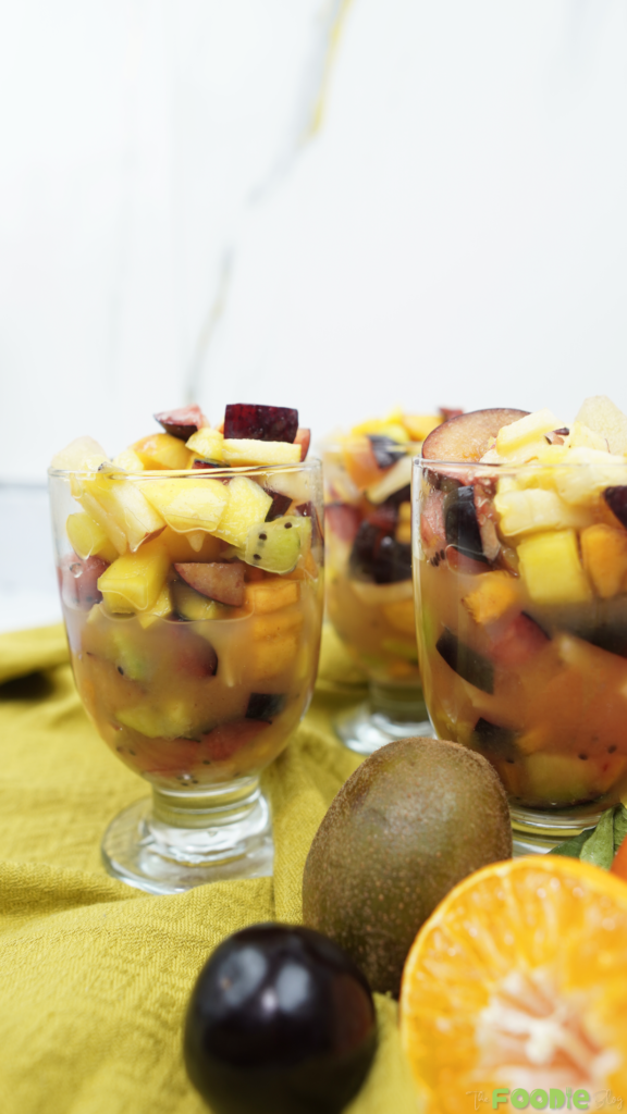 Fruit salad in cups with fresh fruit pieces and citrus dressing in the bottom