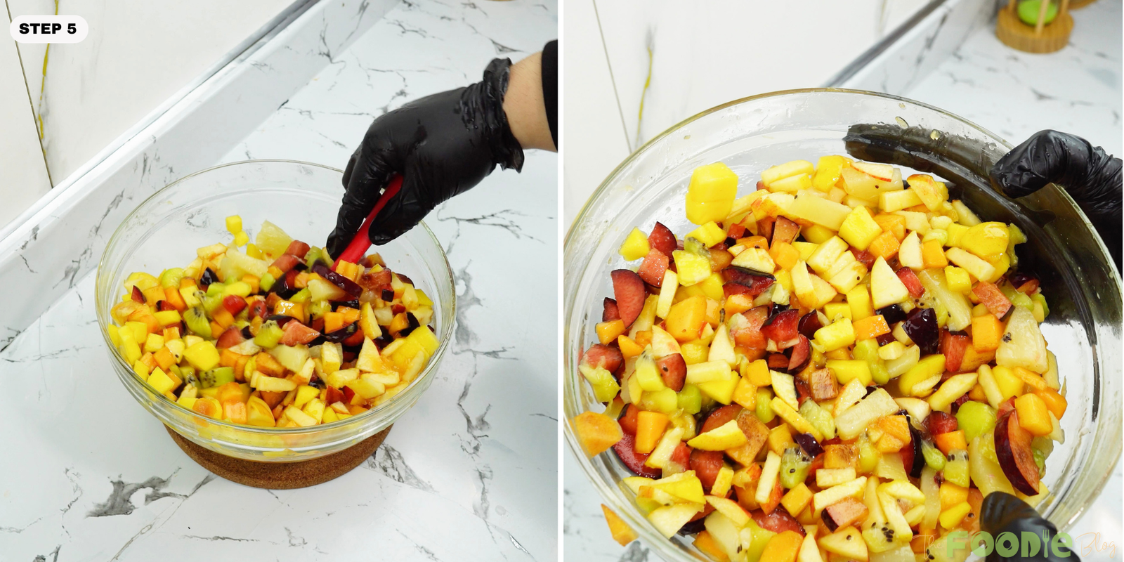 Fruit salad being mixed in a glass bowl with a spoon