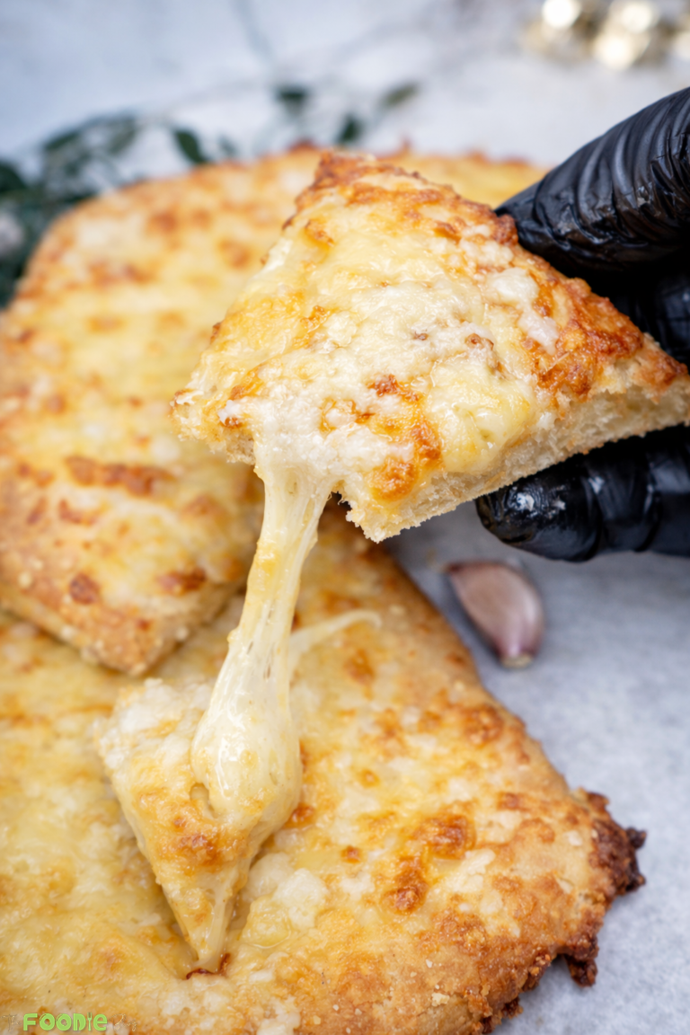 Close-up of garlic cheese bread topping with melted mozzarella and parmesan, browned and bubbly