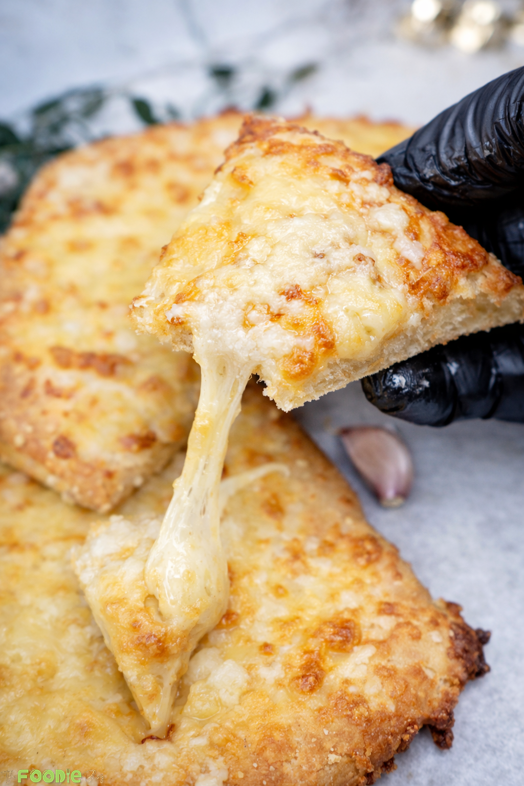 Close-up of garlic cheese bread topping with melted mozzarella and parmesan, browned and bubbly