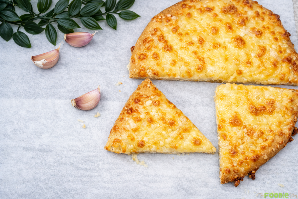 Garlic cheese bread cut into slices on parchment paper with melted cheese and golden spots