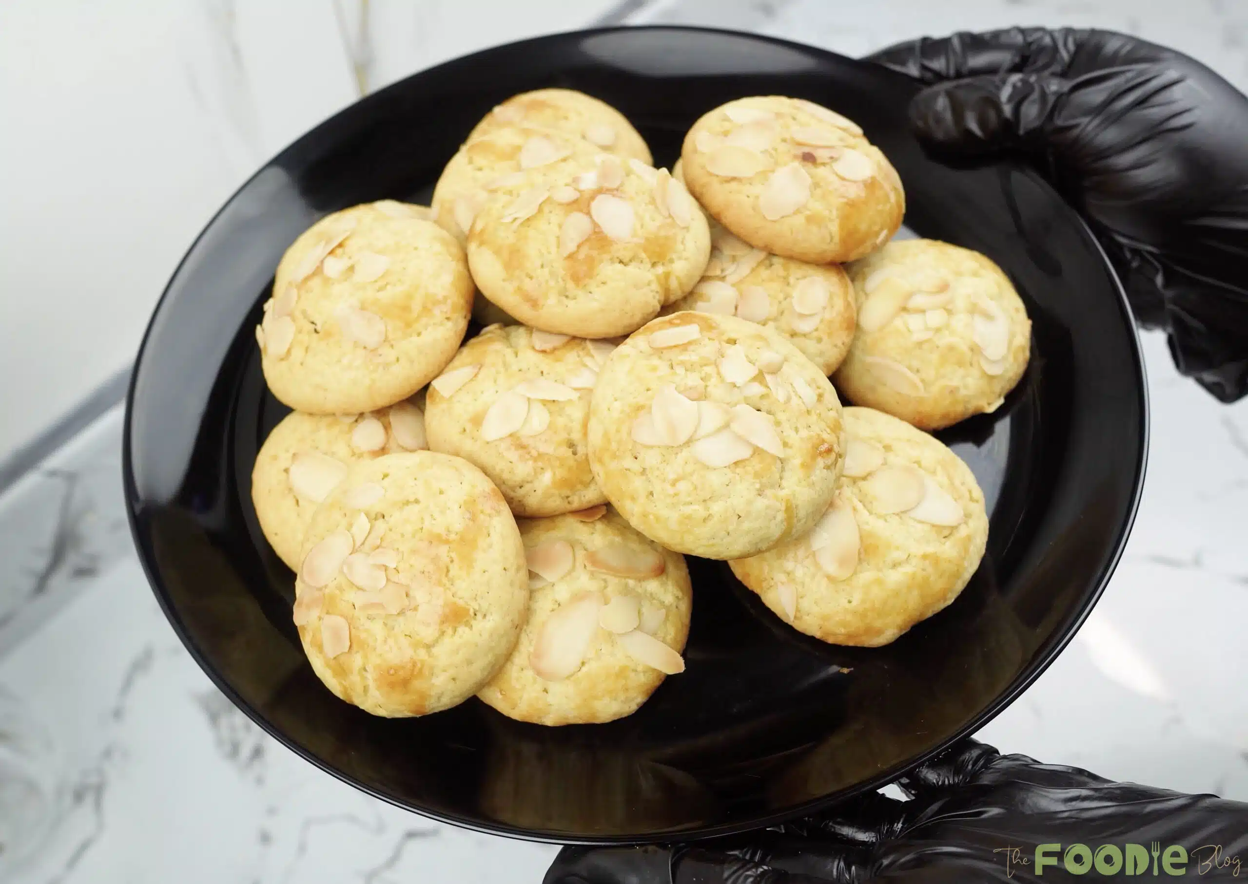 A plate piled with golden almond-topped Greek-style biscuits