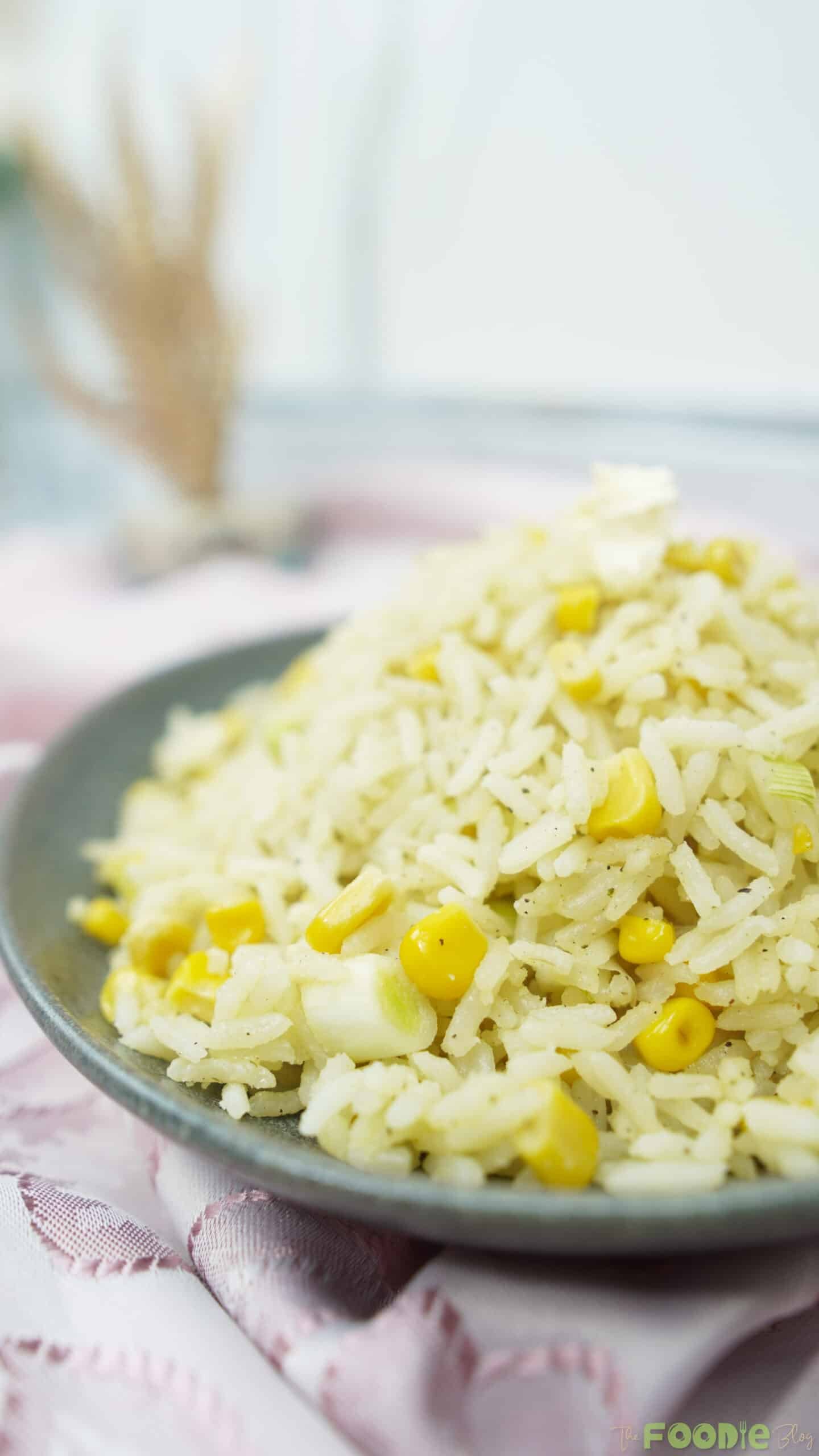 Side view close-up of corn rice with scattered black pepper specks and tender grains
