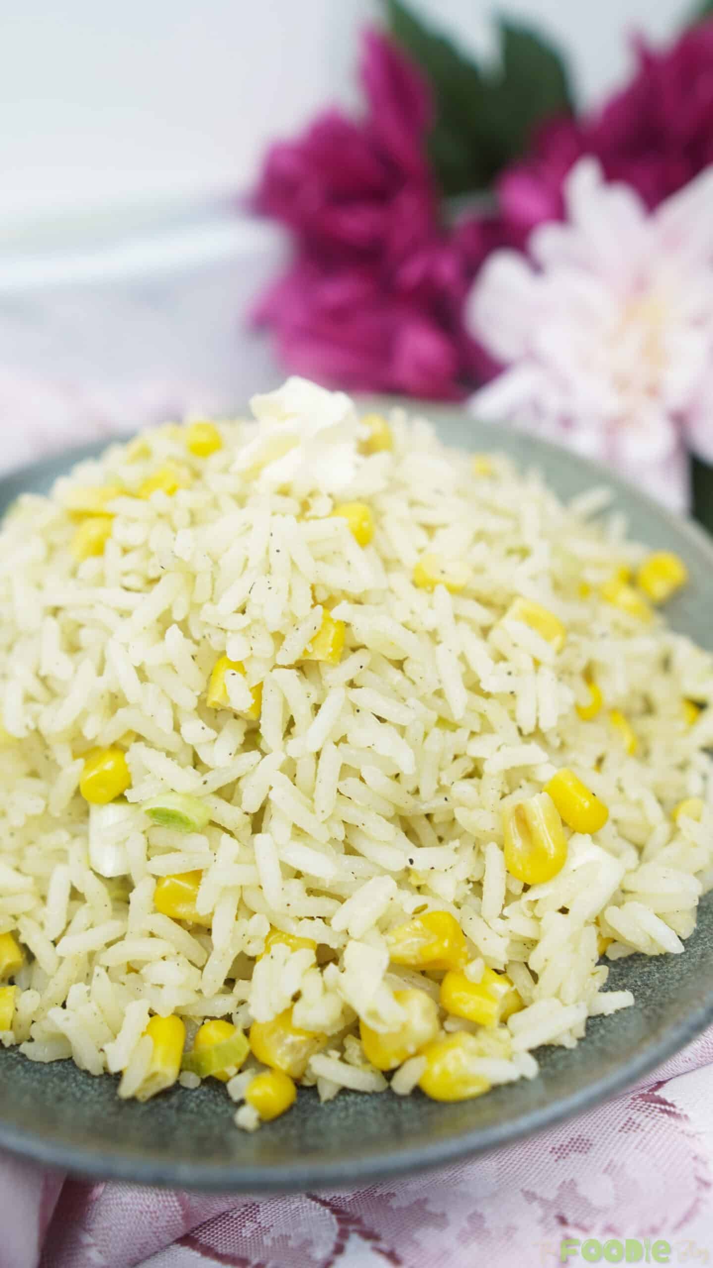 Close-up of buttery corn rice on a gray plate with a soft blurred background