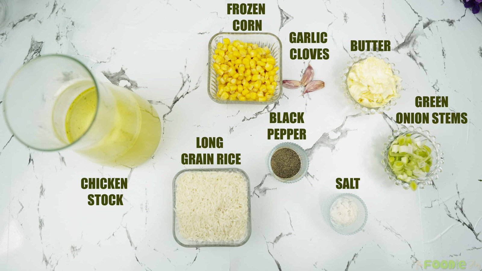 Chicken stock, frozen corn, rice, butter, garlic, salt, pepper, and green onions arranged on a counter