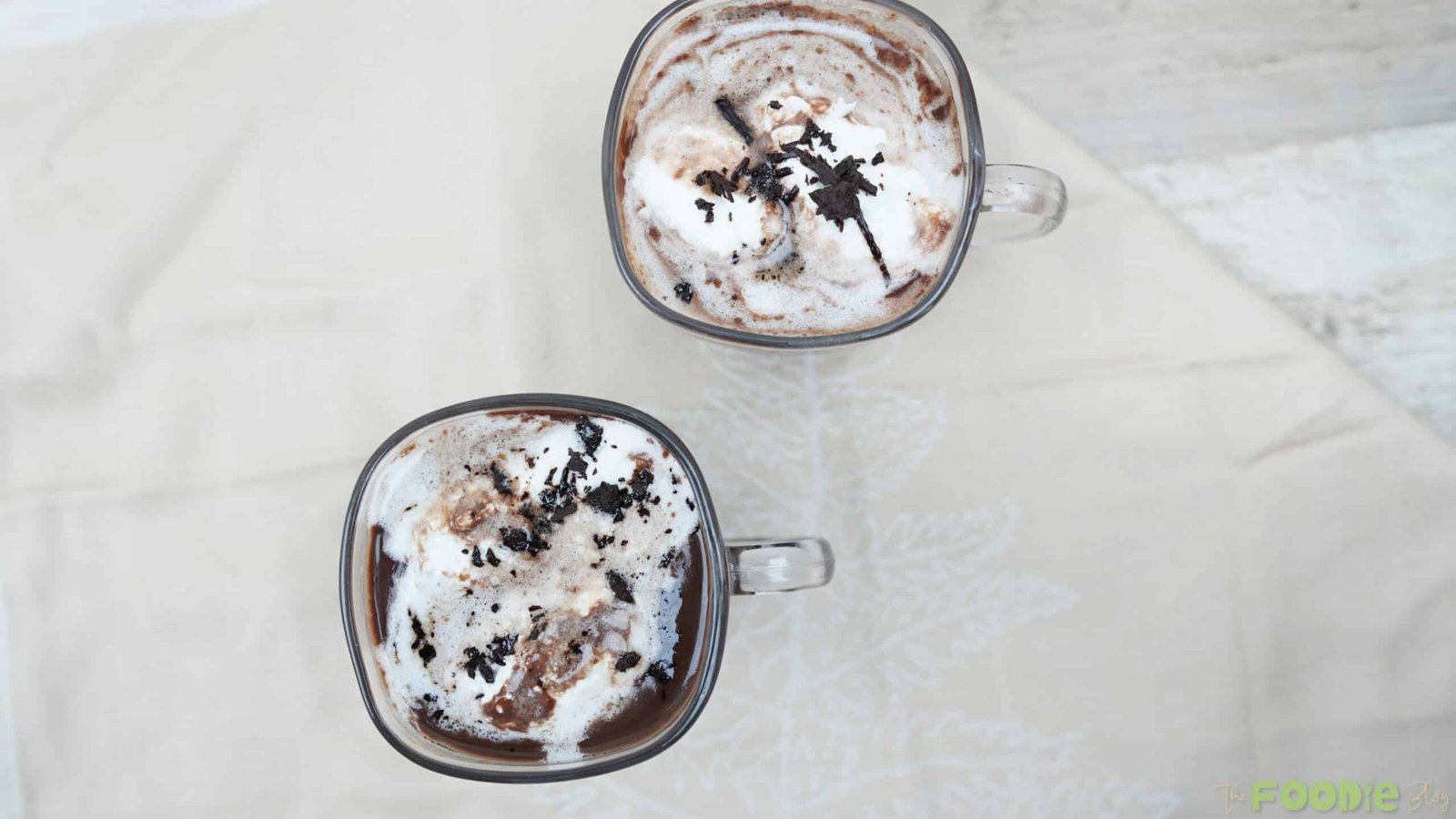 Top view of two glass mugs filled with hot chocolate and whipped cream topping