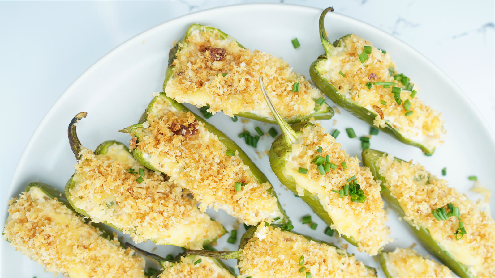 Plate of baked jalapeño poppers topped with golden panko and chopped chives