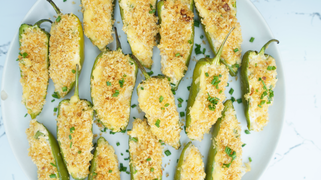 Overhead view of baked jalapeño poppers with crunchy panko topping and chopped chives on a plate