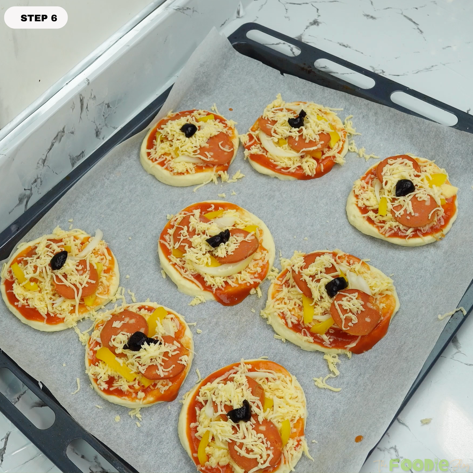 Mini pizzas topped with sauce, cheese, pepperoni, onion, pepper, and olives