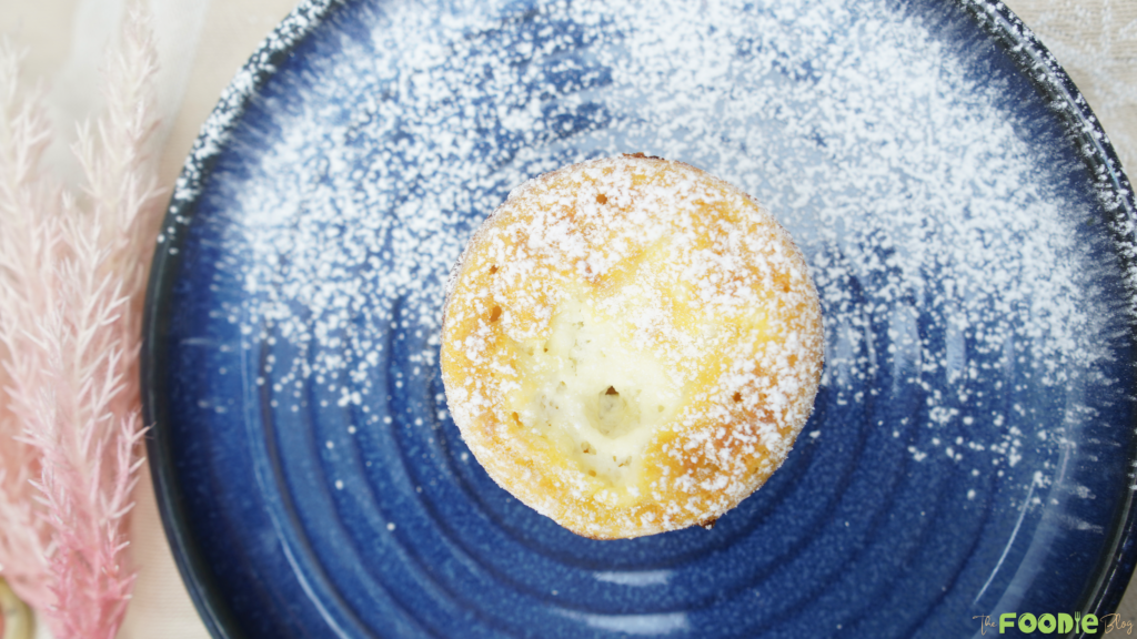 Mini ramekin yogurt cake dusted with powdered sugar on a blue plate