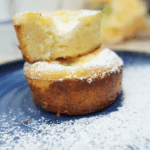 Two mini ramekin cakes stacked with powdered sugar on a blue plate