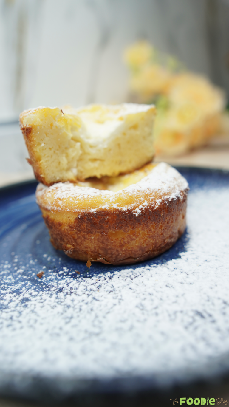 Two mini ramekin cakes stacked with powdered sugar on a blue plate