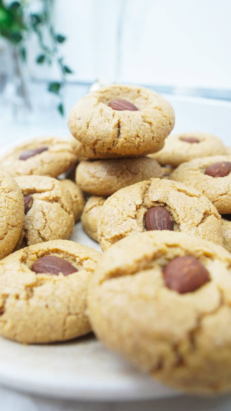 Close-up of peanut butter cookies with crackled tops and an almond pressed in the center