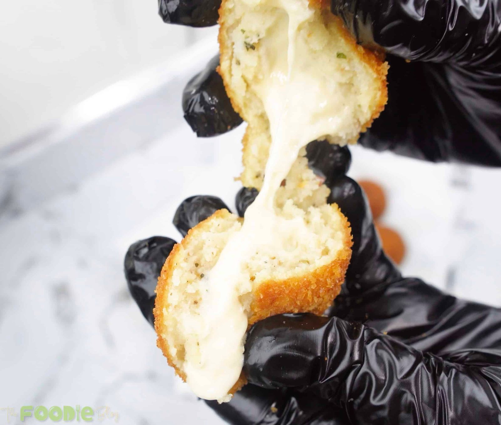 A potato cheese ball broken open with melted cheese stretching