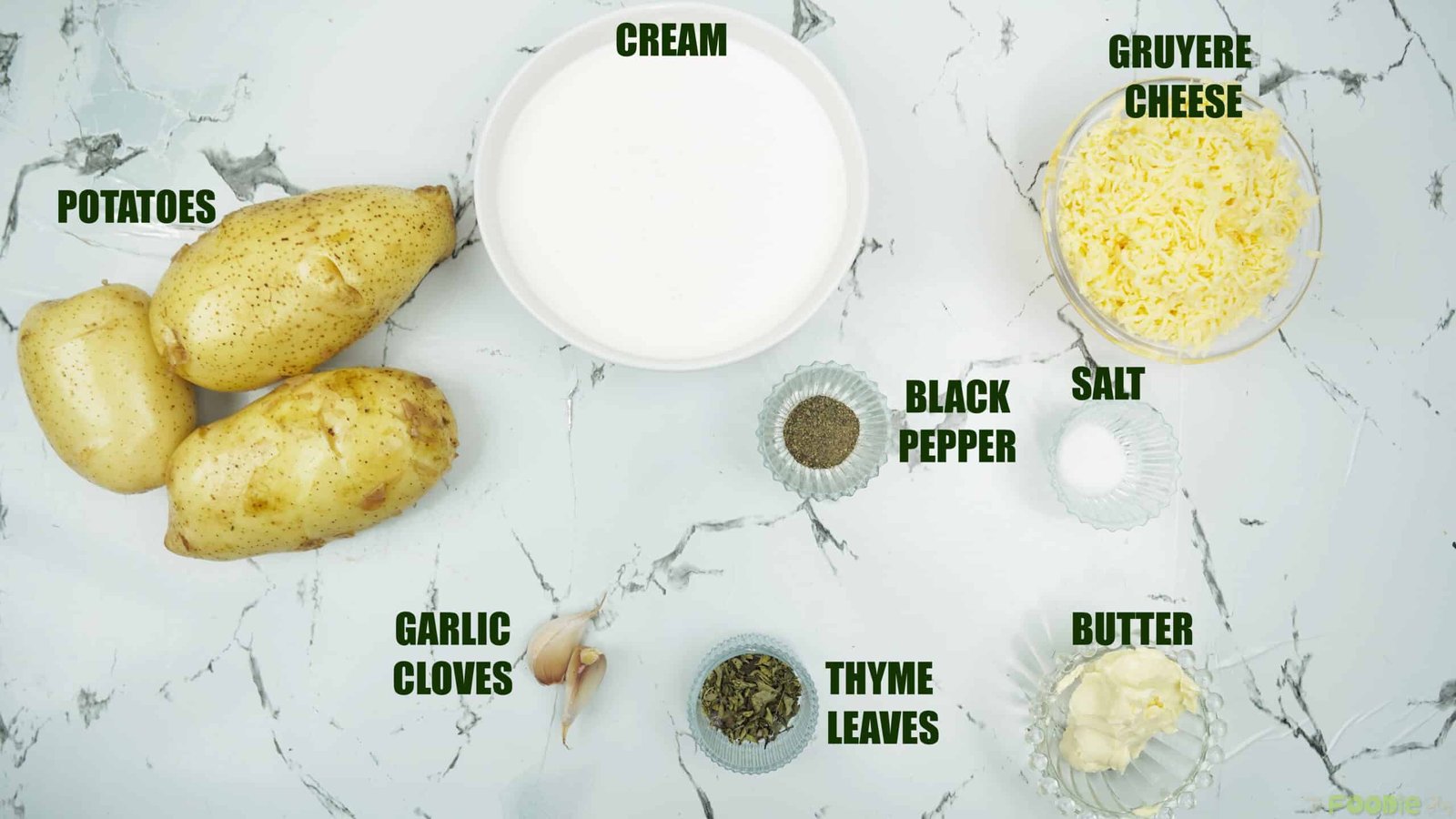 Ingredients for potatoes au gratin including potatoes, cream, Gruyère, garlic, butter, salt, pepper, and thyme