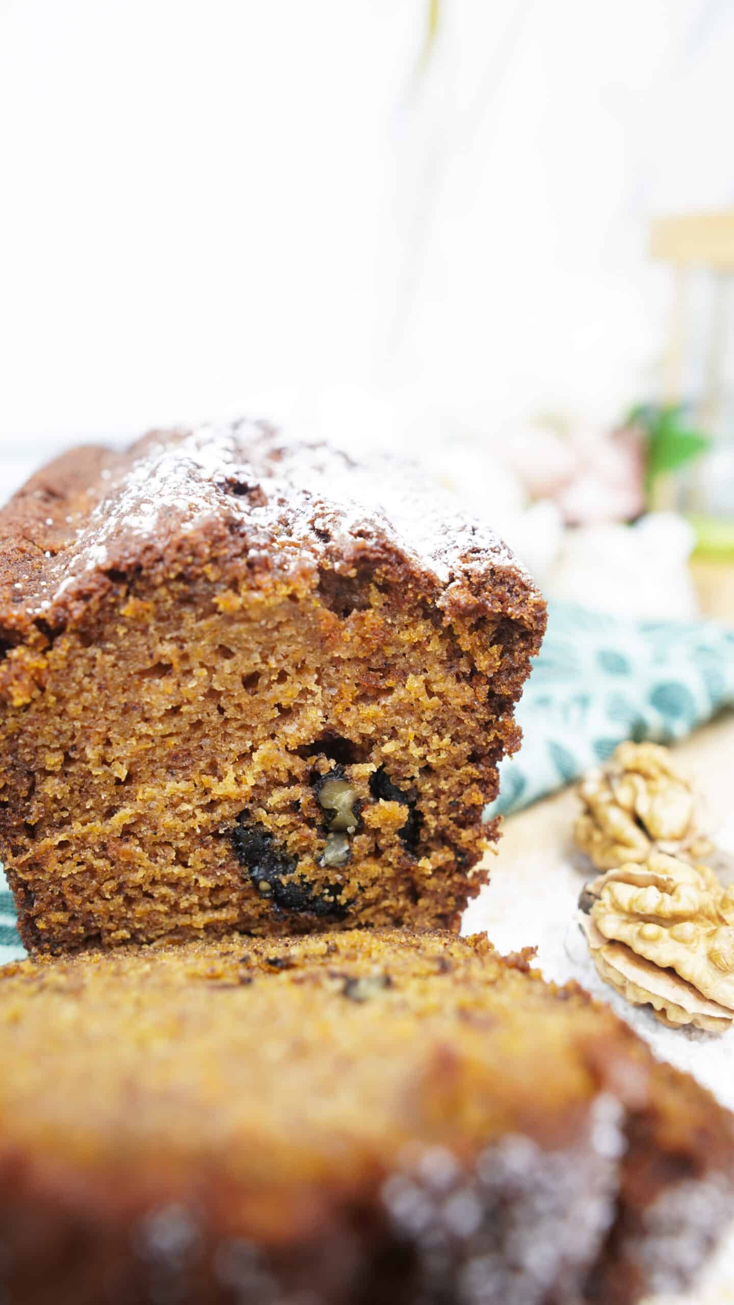 Pumpkin bread slices stacked on a cutting board with walnuts nearby