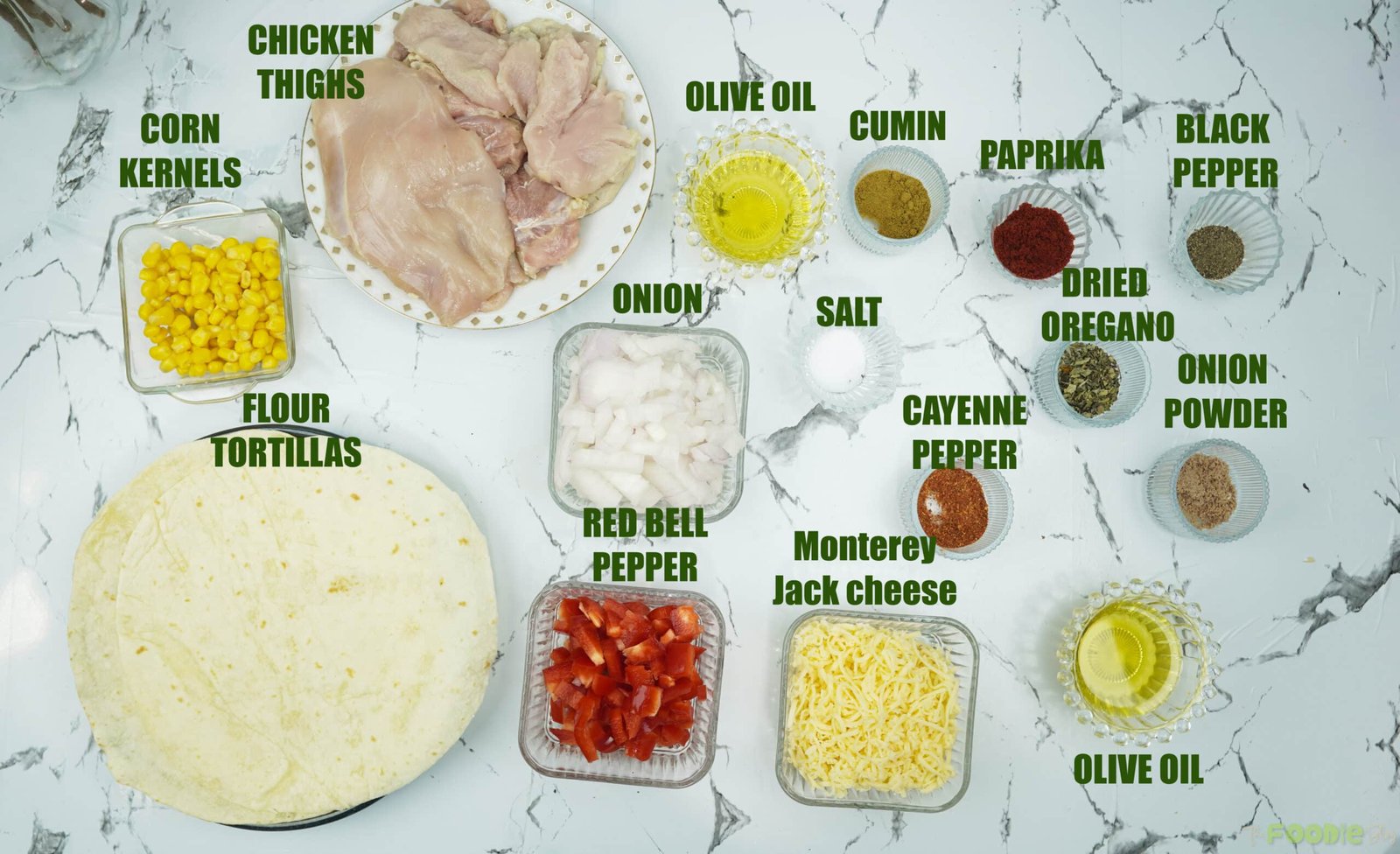 Ingredients laid out for chicken quesadillas including tortillas, chicken thighs, spices, cheese, corn, onion, and bell pepper