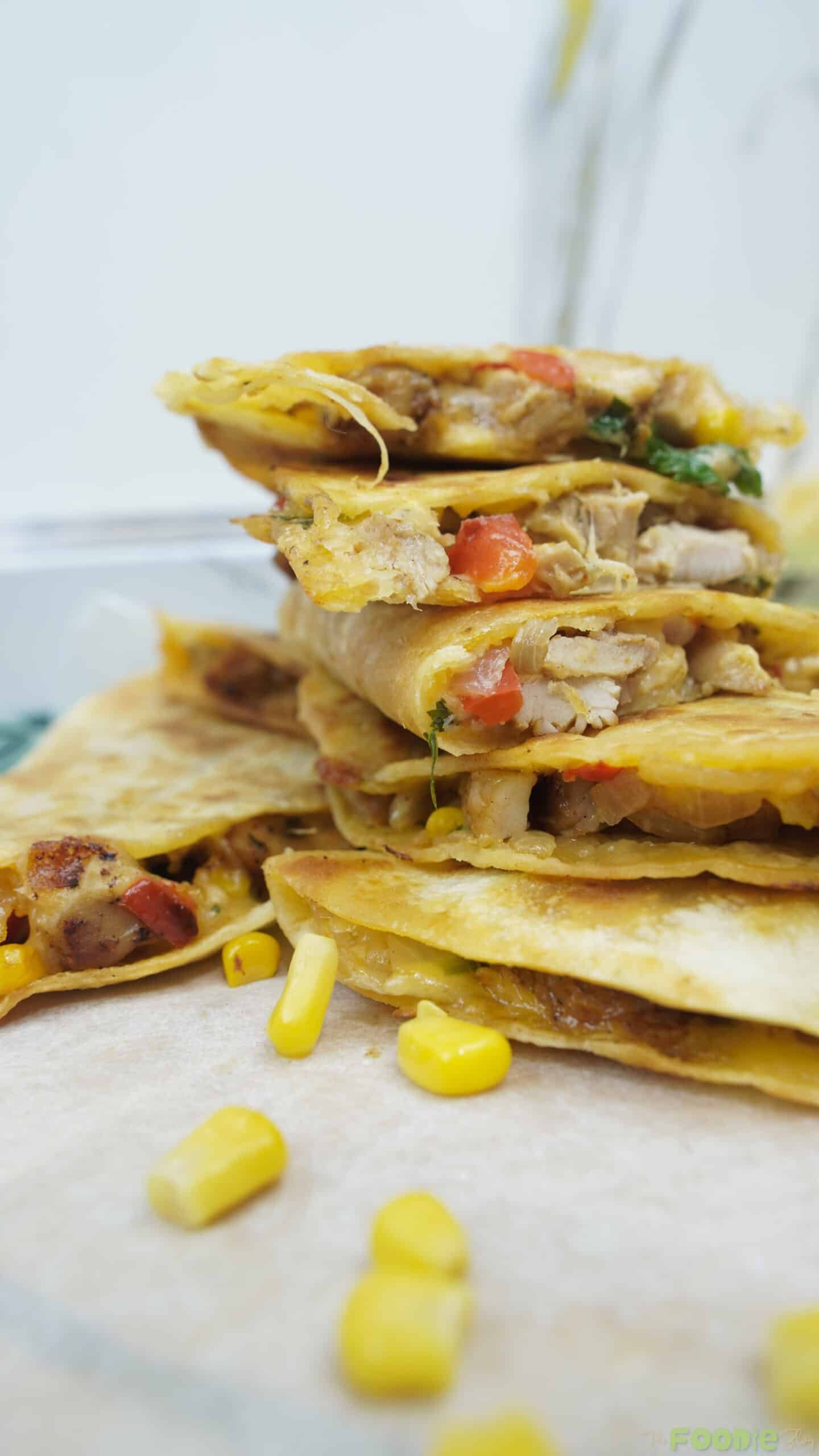 Close-up stack of golden quesadilla wedges with chicken, corn, and melted cheese Caption: Crispy, cheesy chicken quesadilla wedges.