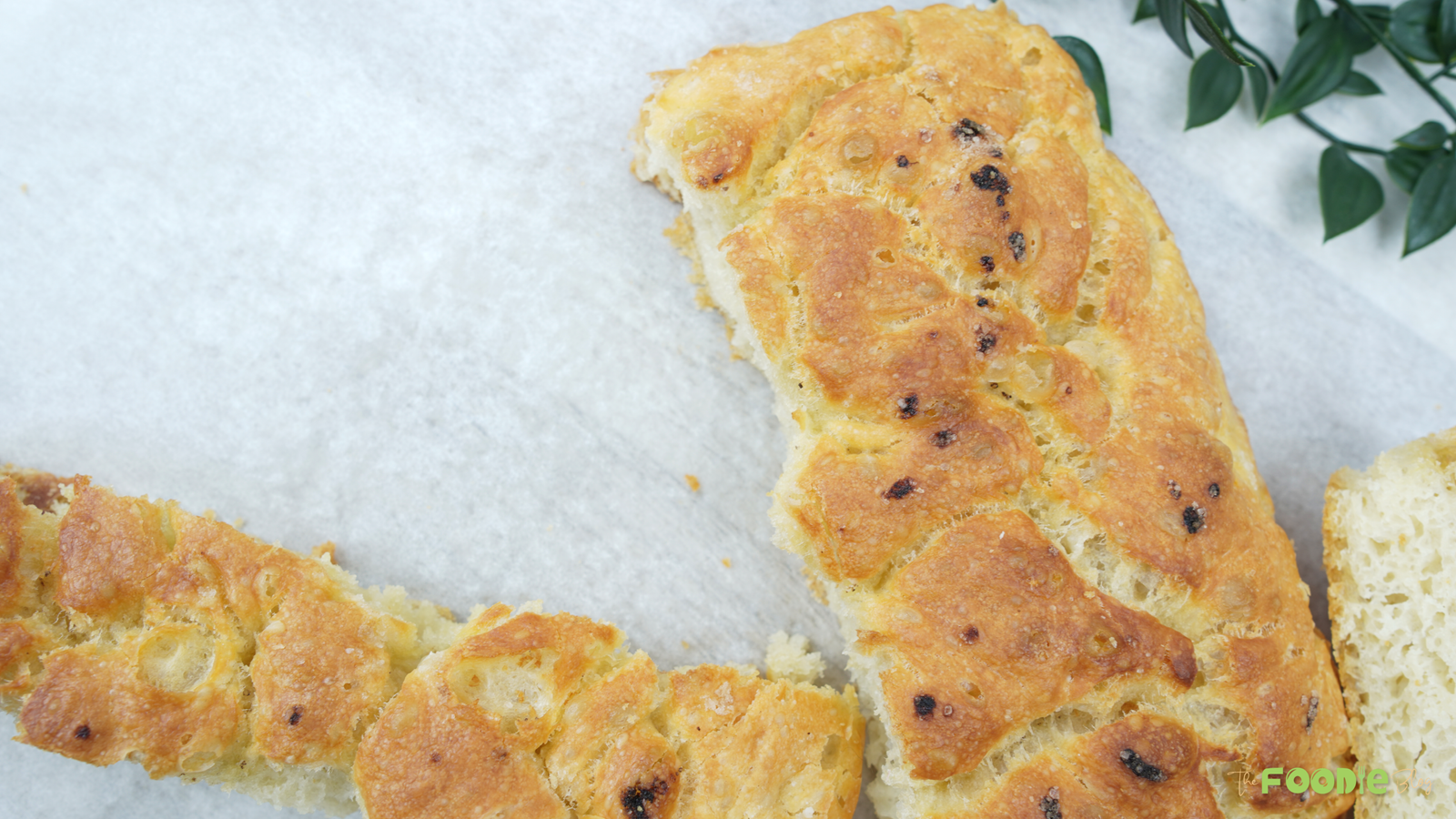 Cut pieces of golden focaccia-style bread on parchment paper with a soft interior visible