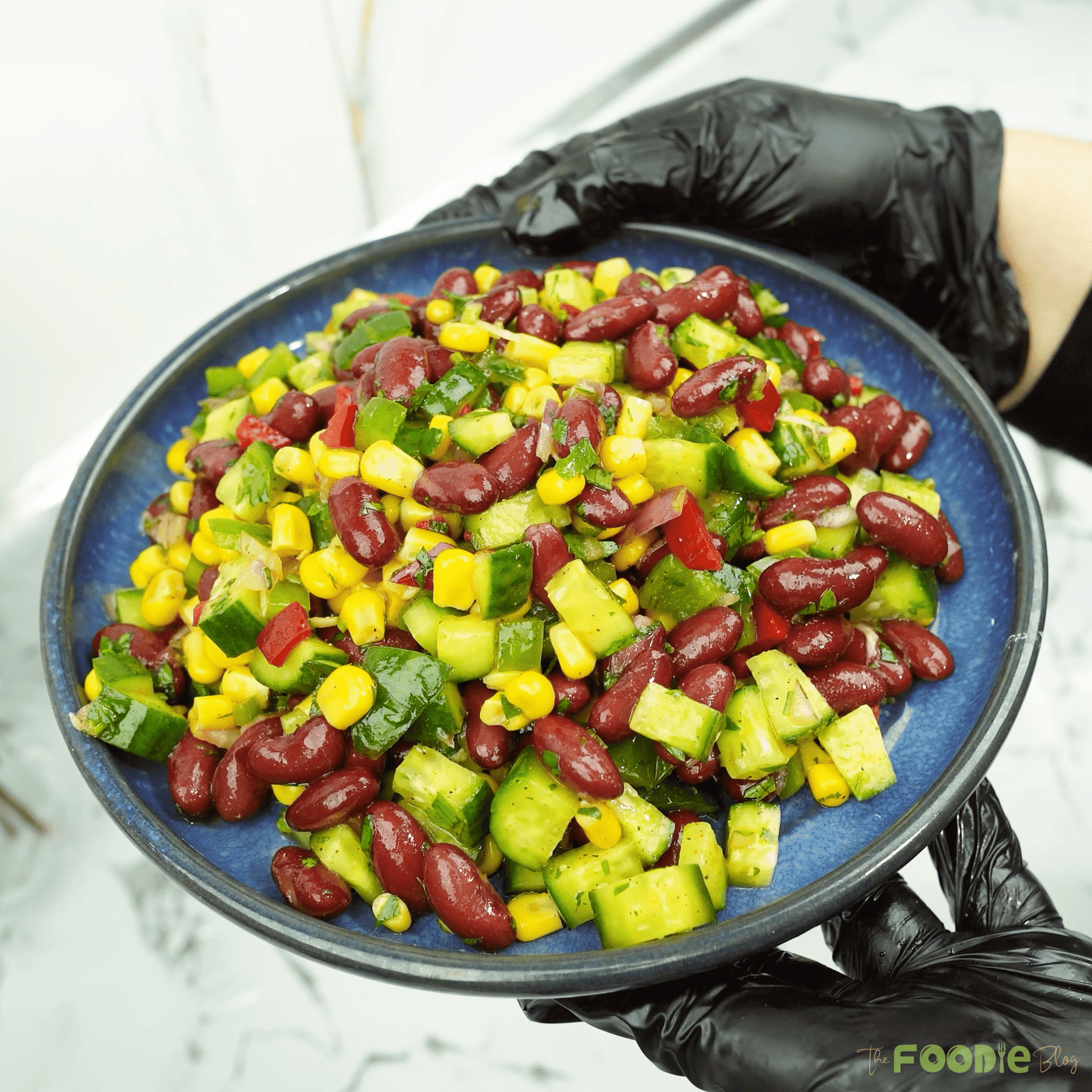 Finished red bean salad served in a blue bowl with visible cucumbers and corn Caption: Ready to serve
