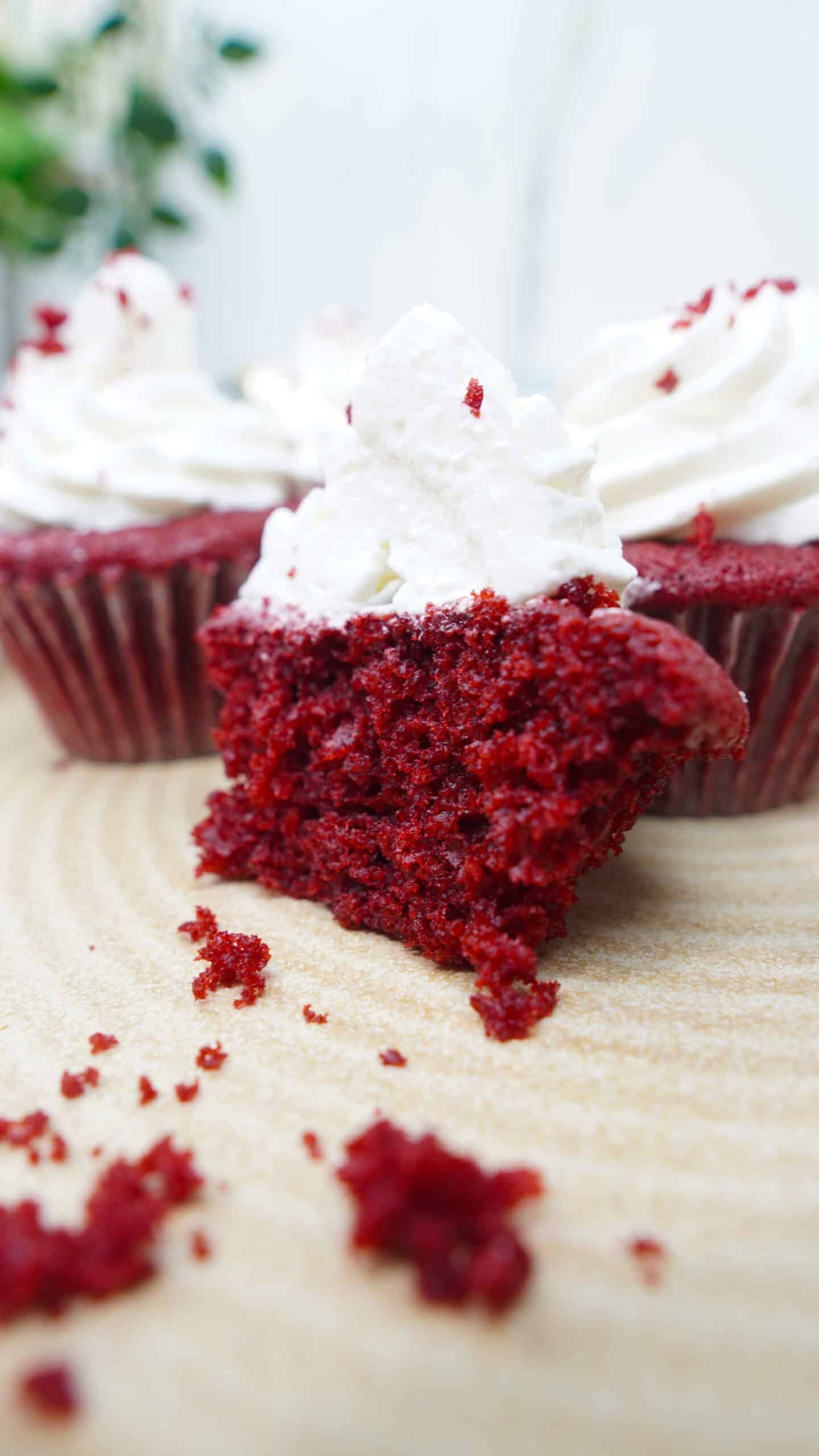 Bite-sized piece of red velvet cupcake with cream cheese frosting in the foreground