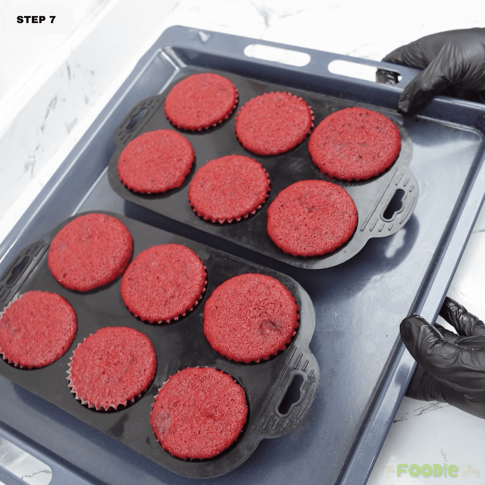 Freshly baked red velvet cupcakes cooling on a tray before frosting