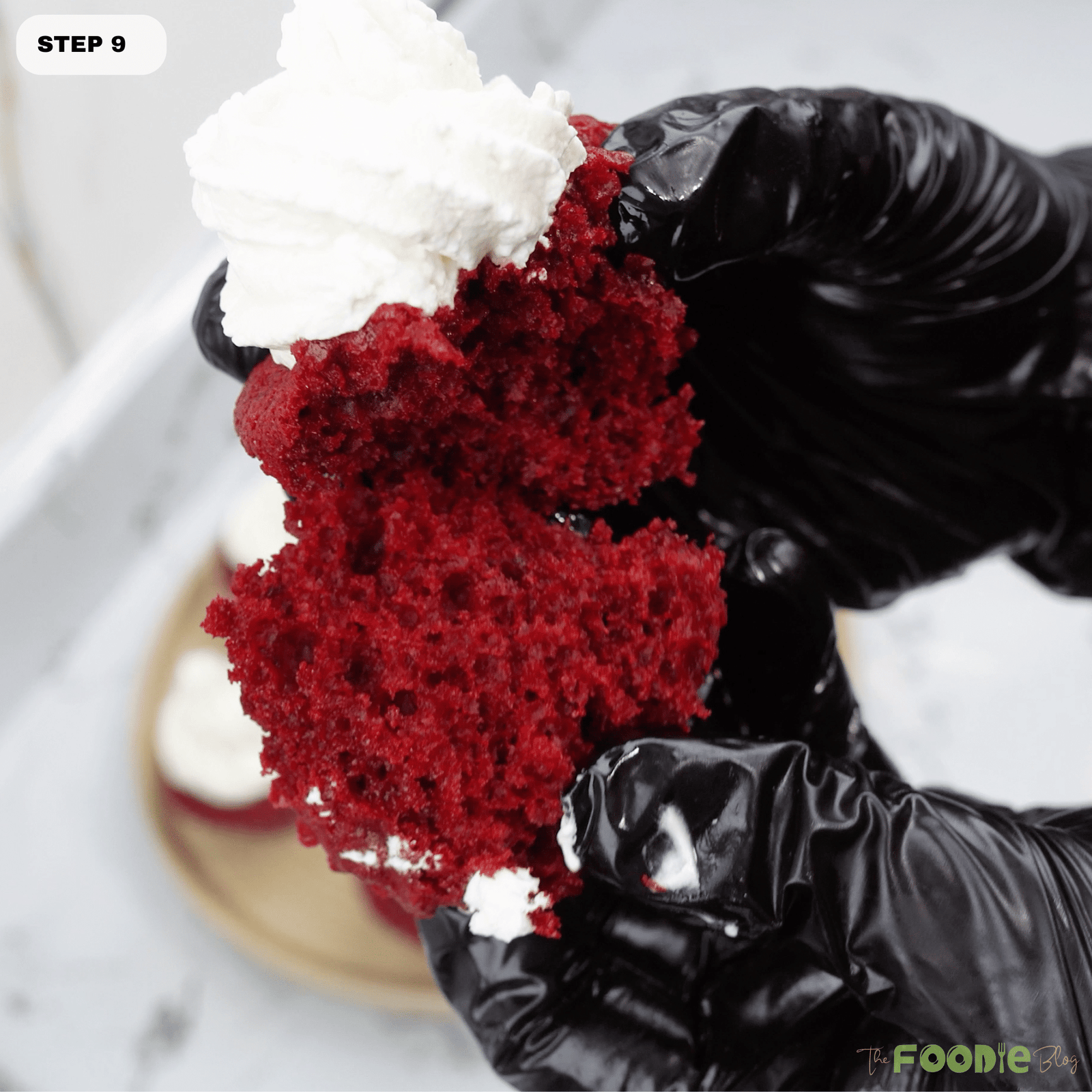 Hands breaking open a red velvet cupcake showing the moist red crumb and frosting