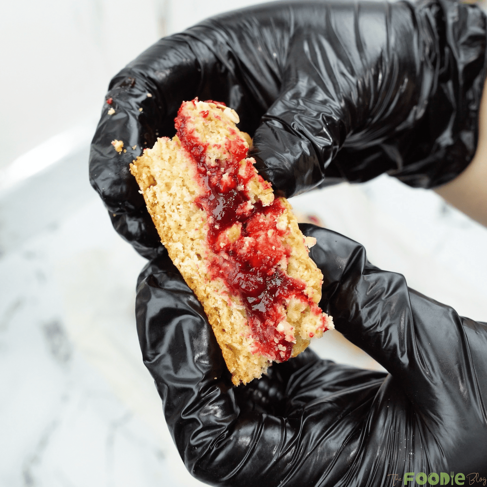 Hand holding a sliced oat bar with raspberry jam in the middle