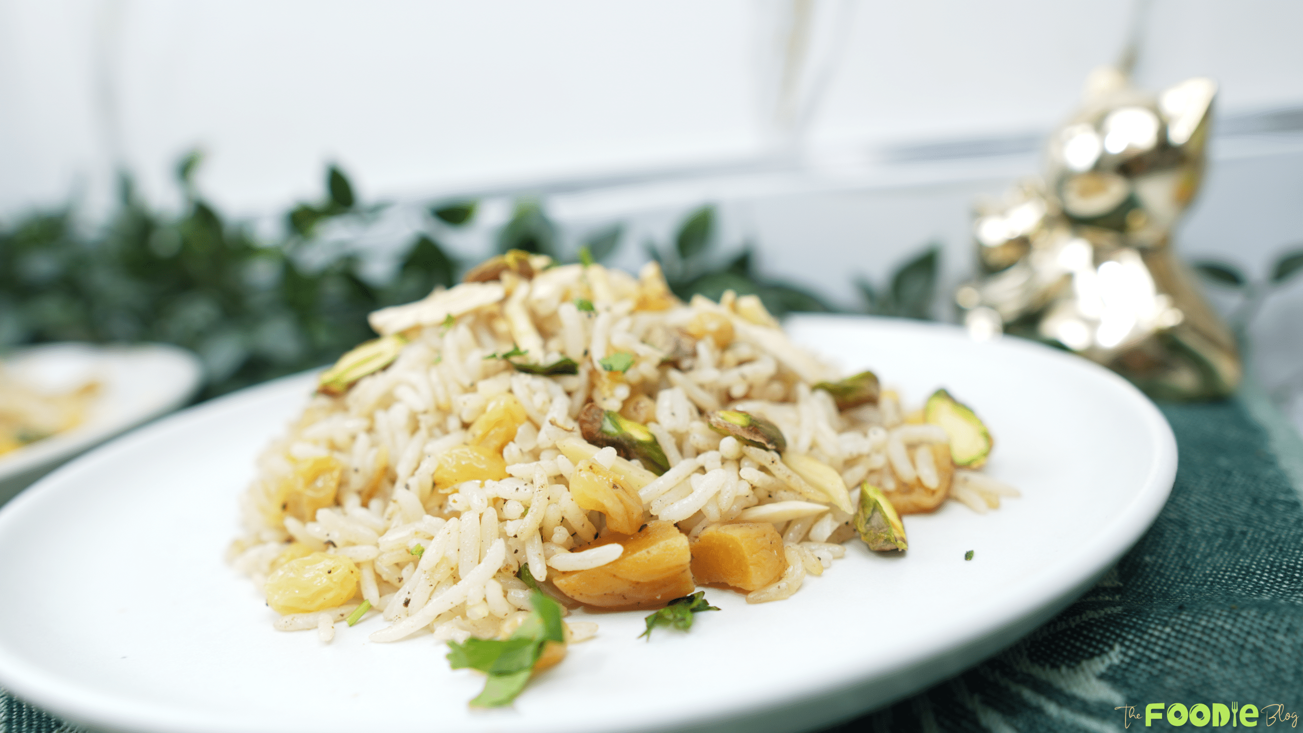 Plated basmati rice pilaf with dried fruit and toasted nuts on a white dish with a soft background
