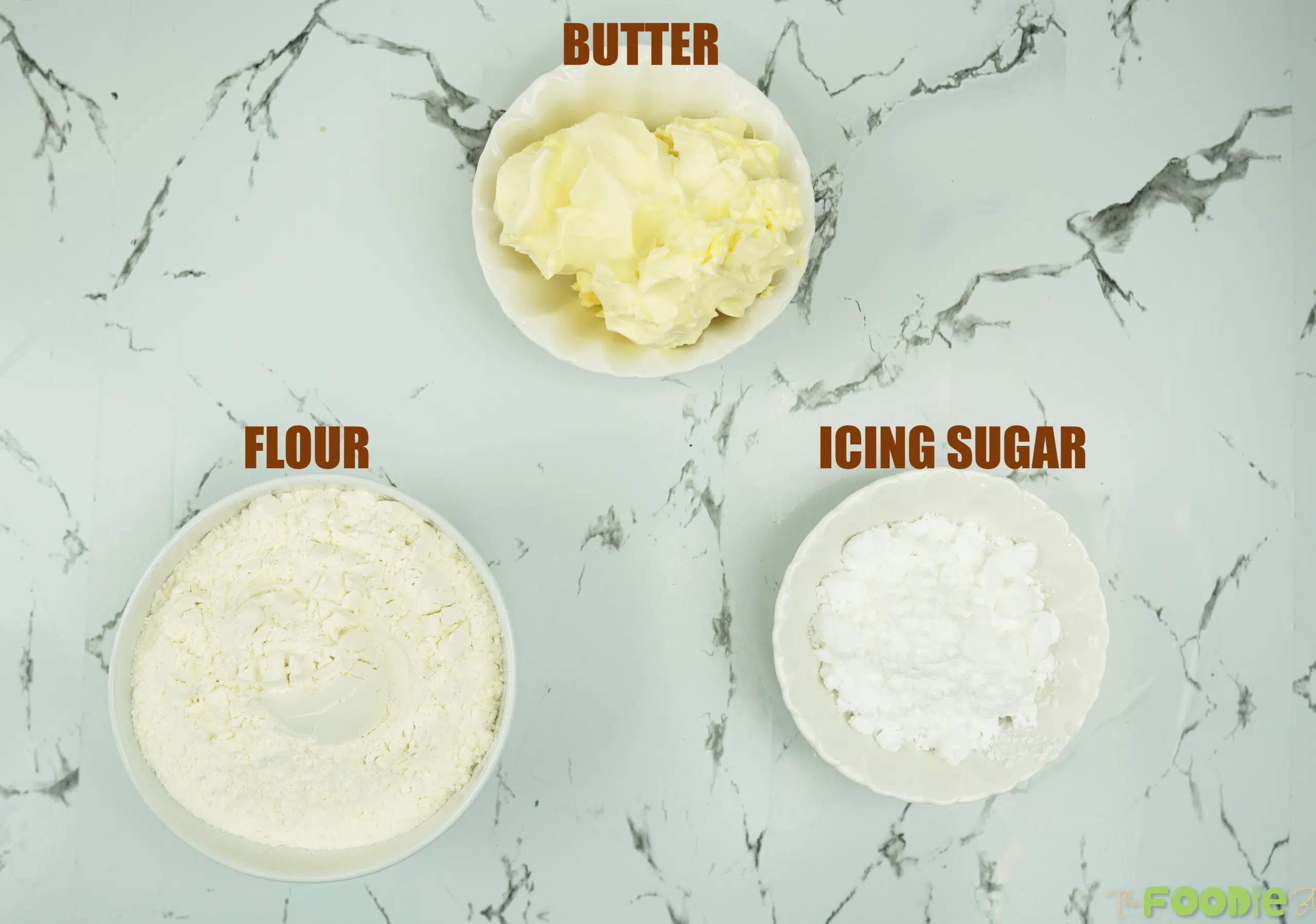 Shortbread cookie ingredients: butter, flour, and powdered sugar in bowls