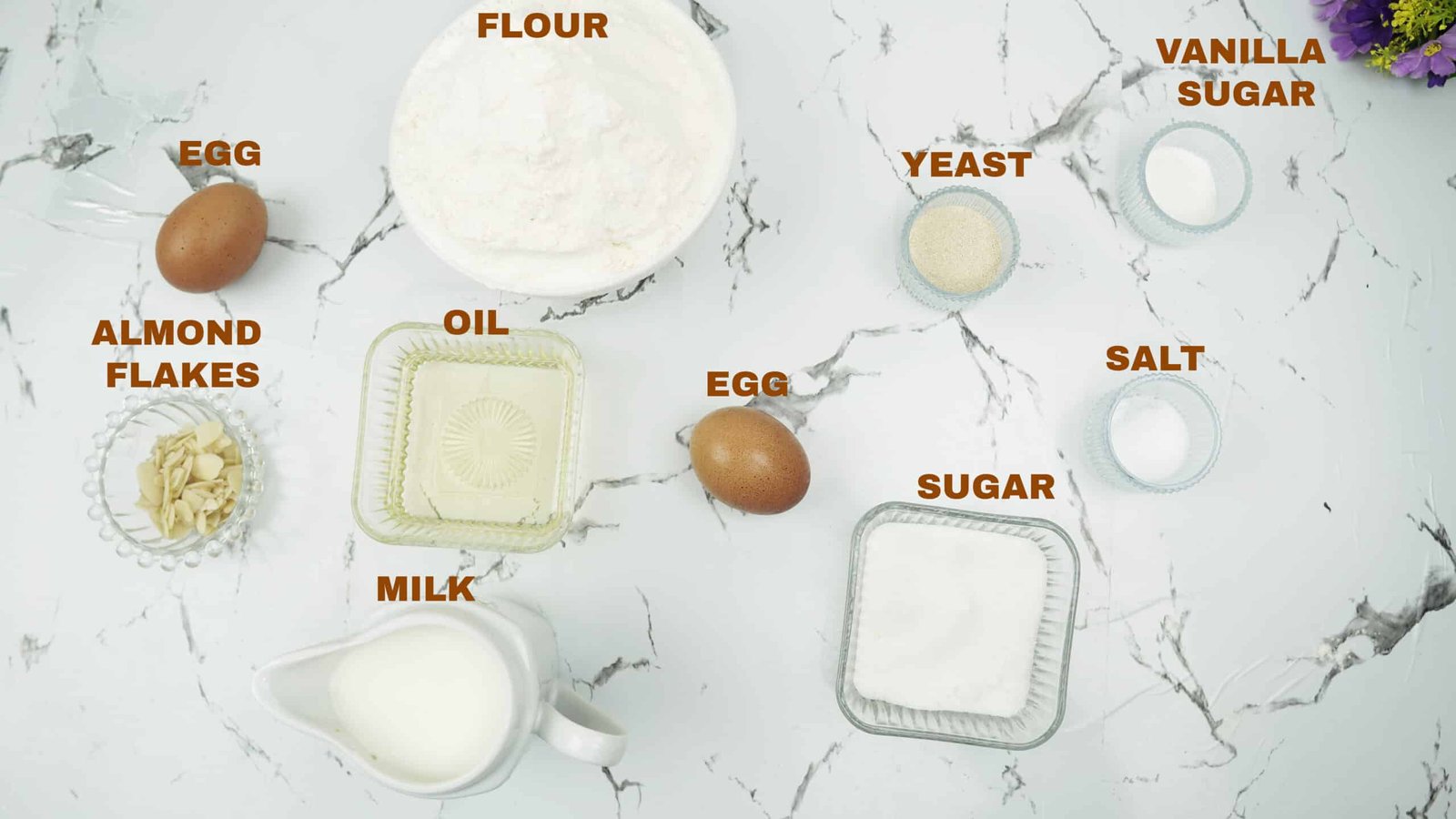 Measured ingredients for brioche bread including flour, eggs, milk, yeast, sugar, and sliced almonds