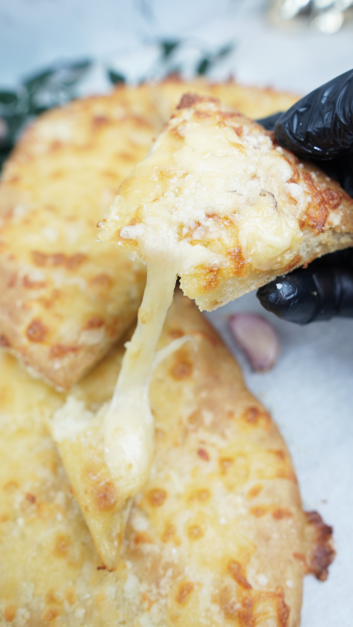 Hand holding a slice with melted mozzarella stretching into a long cheese pull