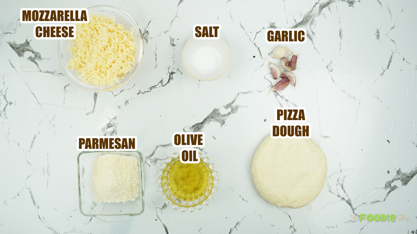 Ingredients arranged on a marble counter: mozzarella, Parmesan, olive oil, garlic, salt, and dough