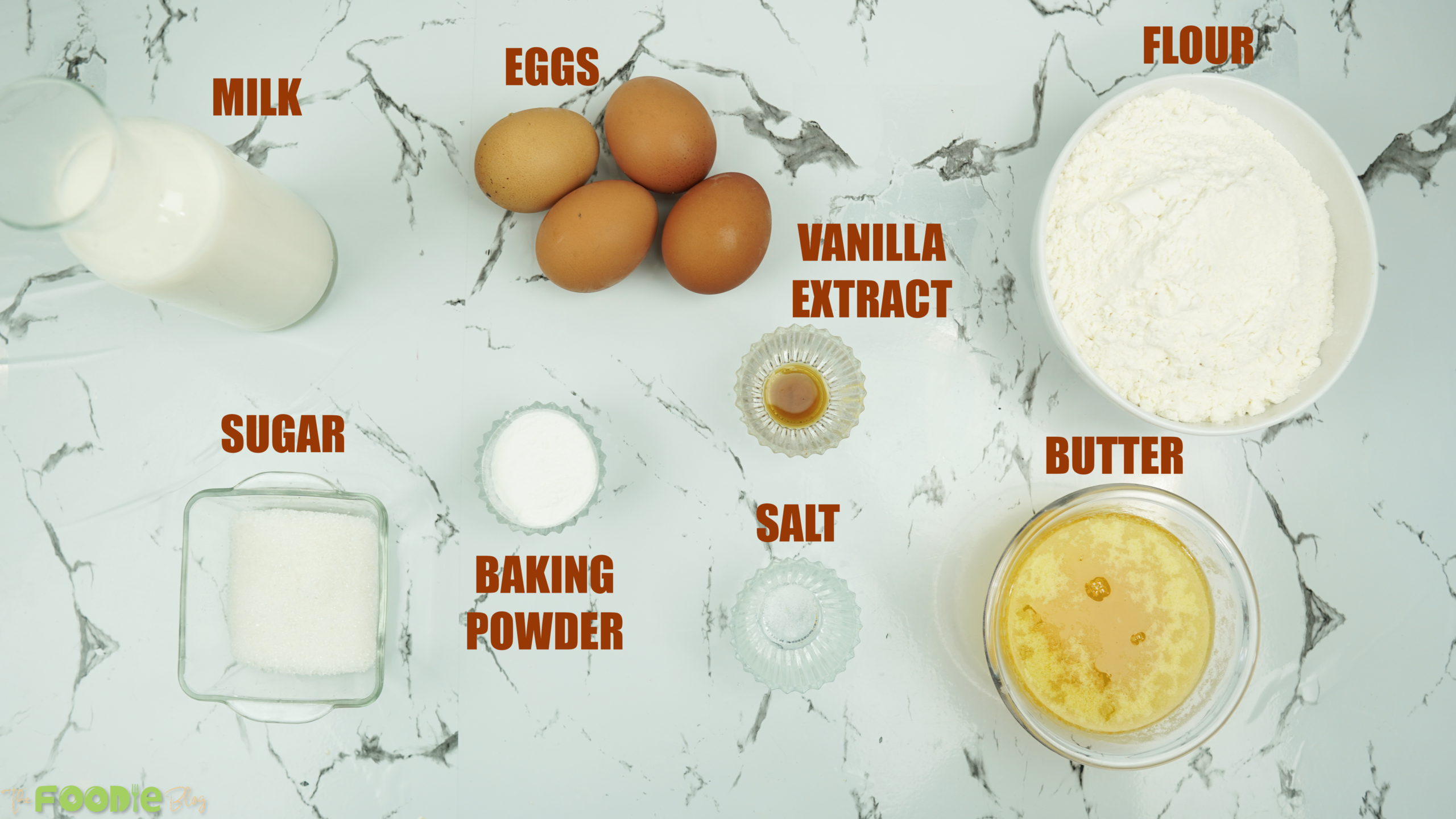 Milk, eggs, flour, sugar, vanilla, butter, salt, and baking powder arranged on a countertop