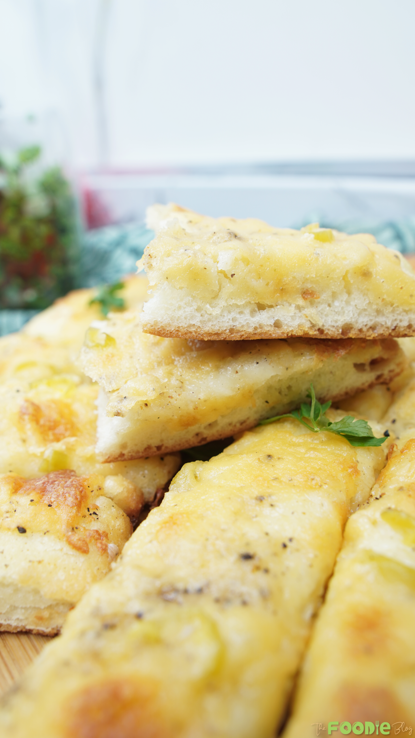 Close-up of a thick, soft slice of cheesy garlic bread stacked on other pieces