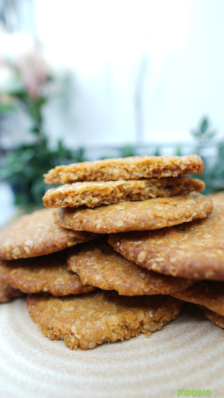 Stack of golden oat-and-coconut biscuits on parchment paper