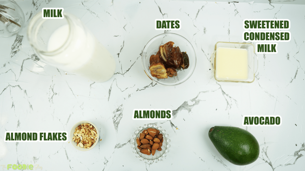 Overhead ingredients for avocado date almond drink including milk, dates, avocado, almonds, condensed milk, and almond flakes