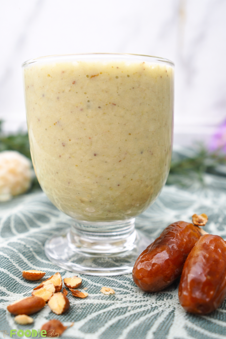 Avocado date almond drink in a glass, topped with chopped almonds
