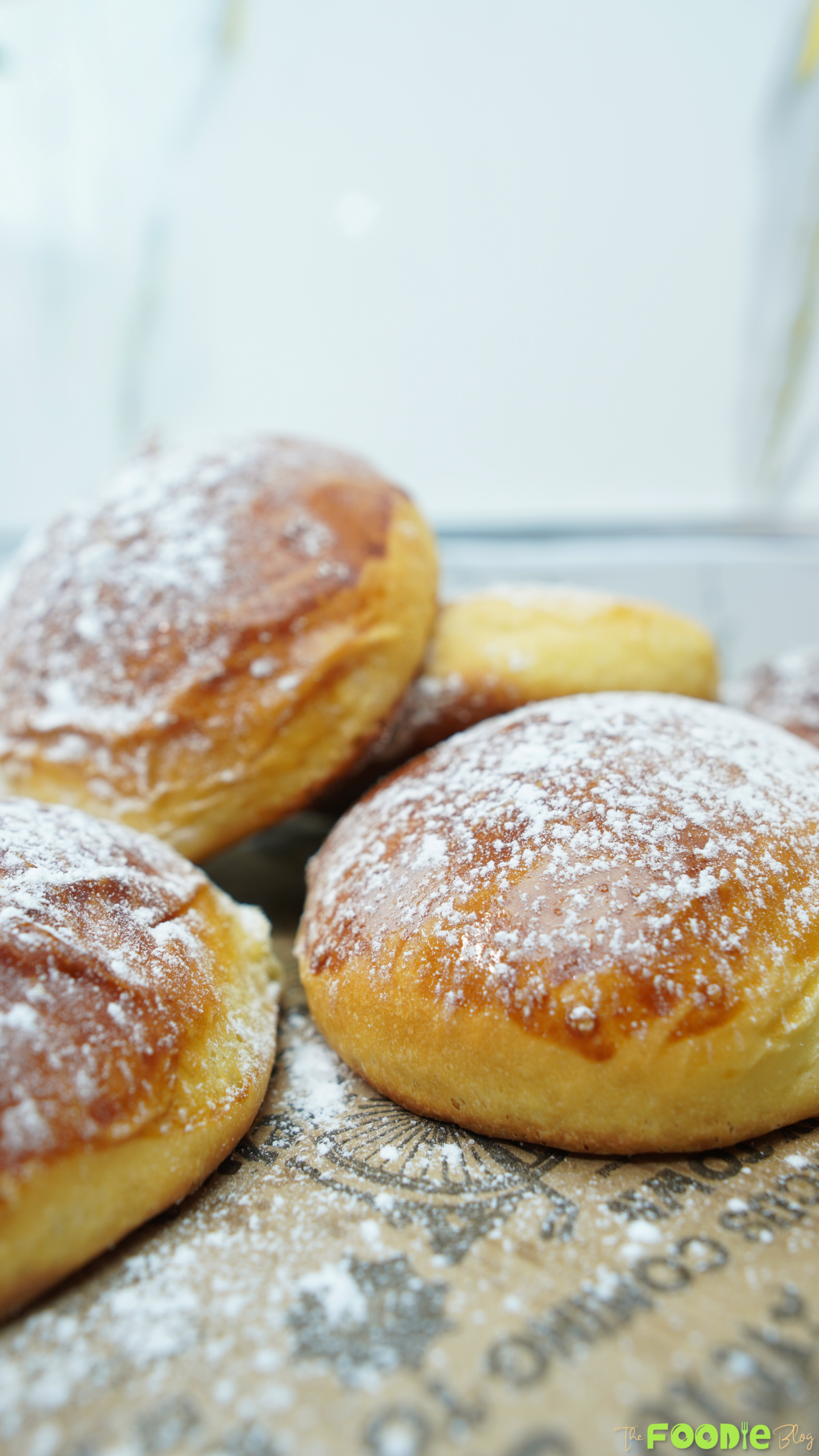 Whole brioche buns dusted with powdered sugar on a serving board
