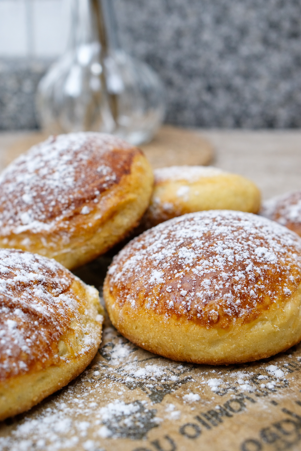 Golden brioche with chocolate doughnuts sprinkled with powdered sugar on a rustic surface.