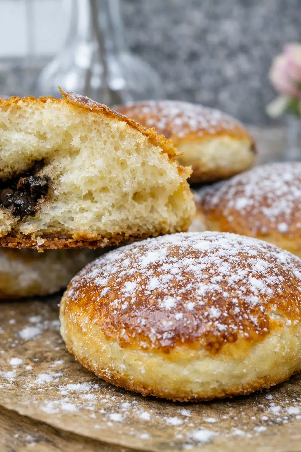 Brioche with chocolate doughnuts dusted with powdered sugar on a wooden board.