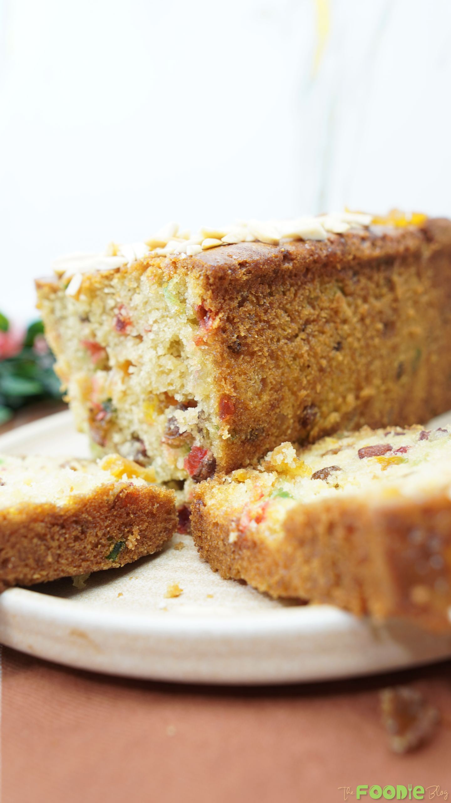 Candied fruit cake loaf with sliced pieces on a plate, showing colorful fruit bits inside