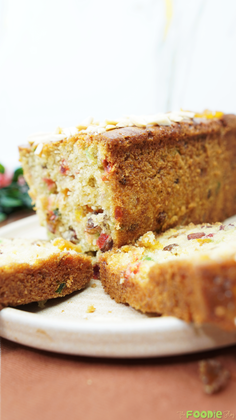 Sliced candied fruit cake loaf showing a moist crumb with raisins and mixed candied fruit pieces.